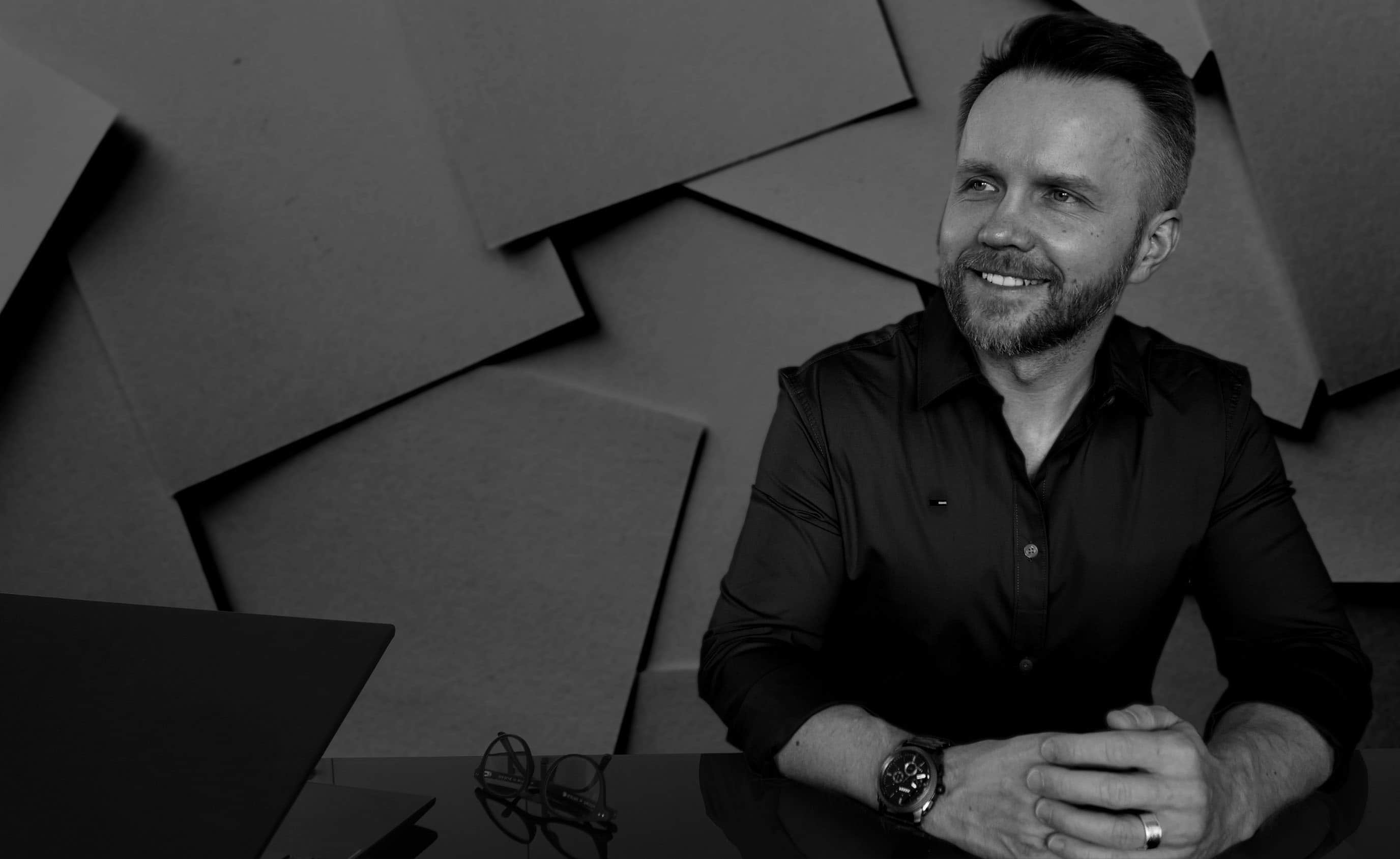 Der Software-Entwickler, Herr Kukiz, sitzt lächelnd in seinem Office.